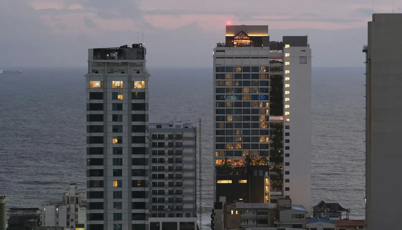 Prédios altos de frente para o mar ao entardecer, vistos de uma avenida à beira-mar