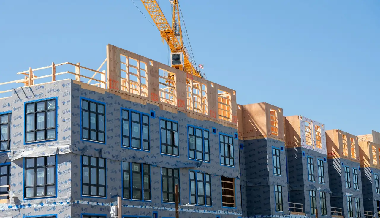 Prédio residencial em construção com guindaste sob céu azul
