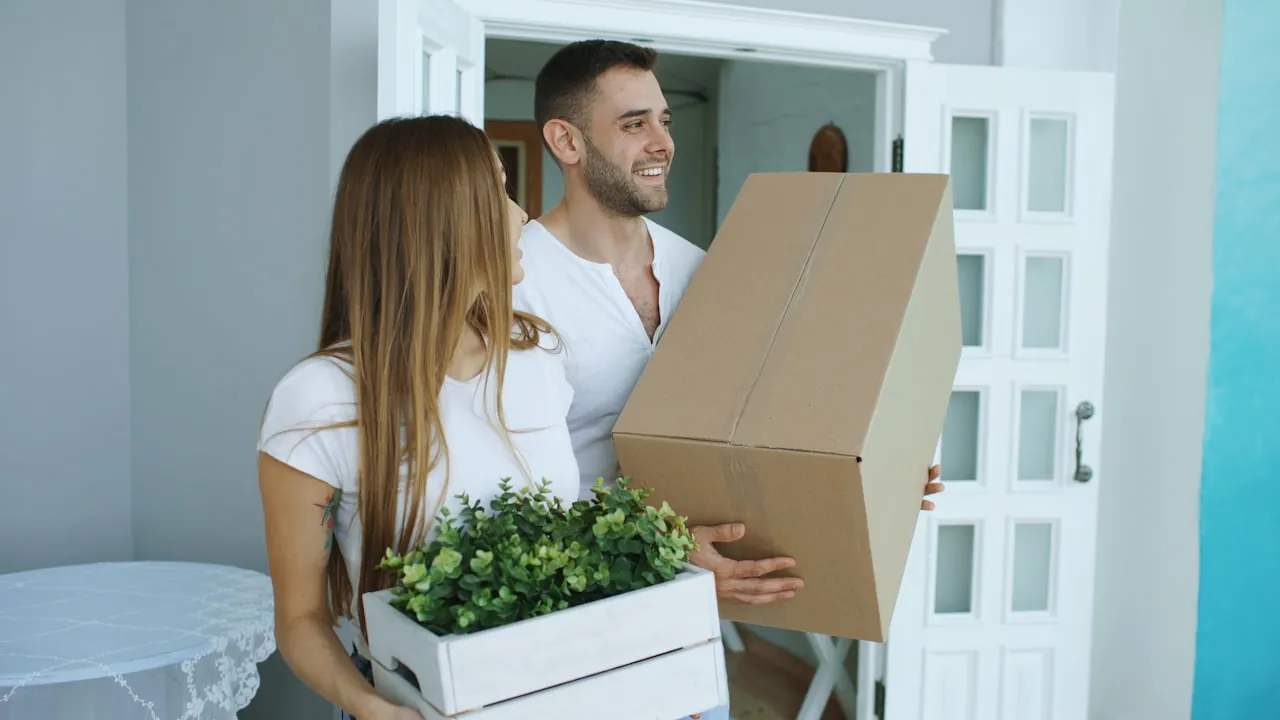 Casal recebendo as chaves do primeiro apartamento na porta de entrada do imóvel