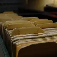 Fichário de arquivo com fichas de papel amarelado e etiquetas escritas à mão