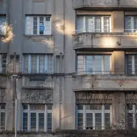Fachada envelhecida de prédio residencial, com janelas antigas e pichação