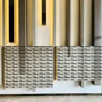 Parede de caixas de correio numeradas de 78 a 231 no hall de um prédio residencial, com piso claro e painéis verticais iluminados