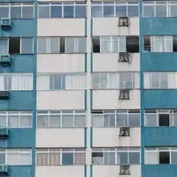 Fachada de prédio residencial de azulejo azul e branco, com apartamentos iguais empilhados, janelas de vidro e aparelhos de ar-condicionado