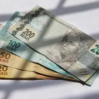 Cédulas de 20, 50, 100 e 200 reais abertas em leque sobre uma superfície clara